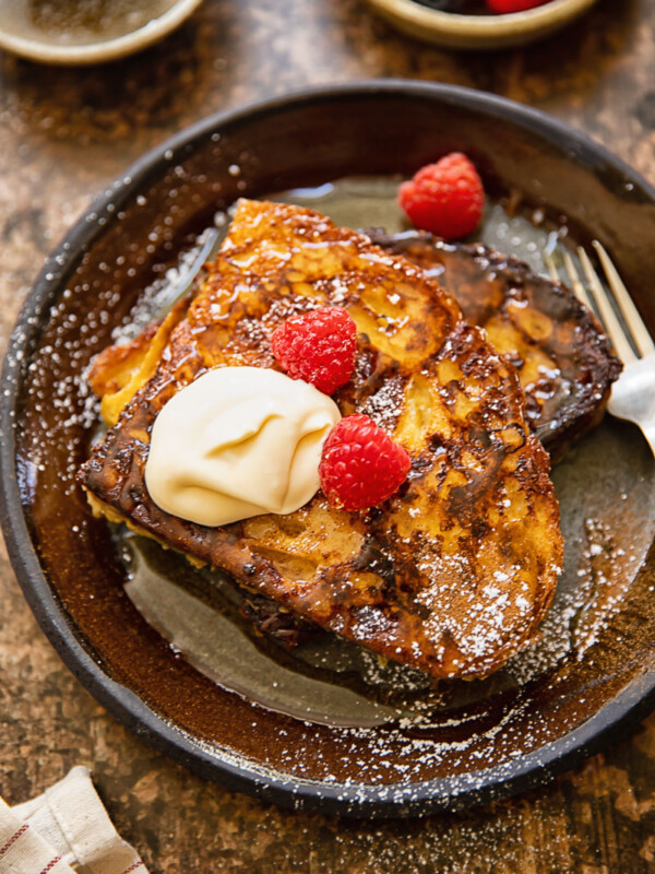 Top down shot of french toast with creme fraiche and raspberries on a plate