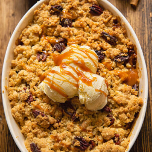 Top down view of ice cream on a apple crisp topped with pecans in a baking dish