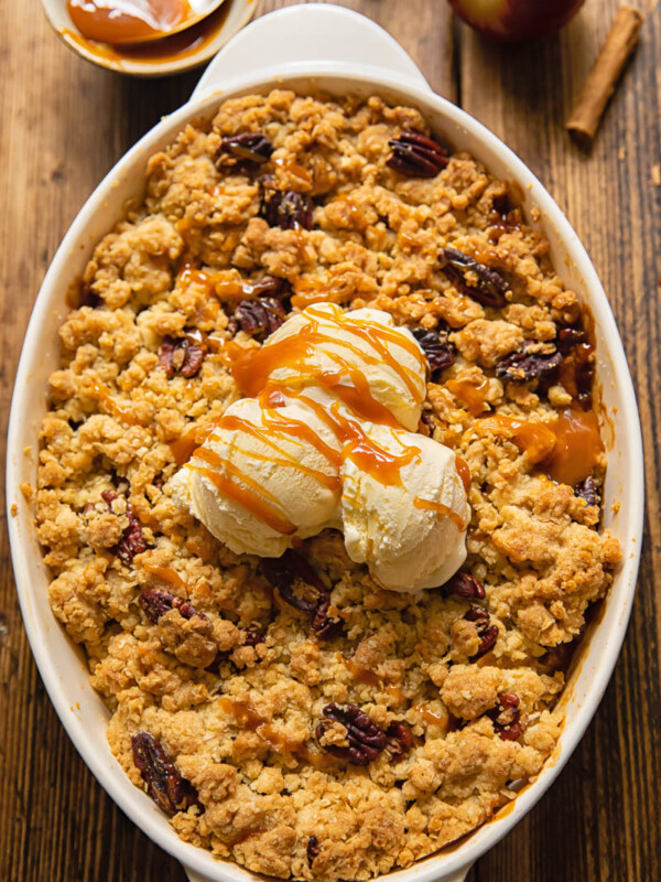 Top down view of ice cream on a apple crisp topped with pecans in a baking dish