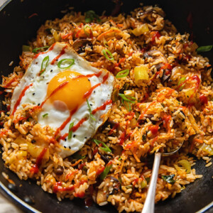 Wok with a spoon in fried rice with a fried egg on top