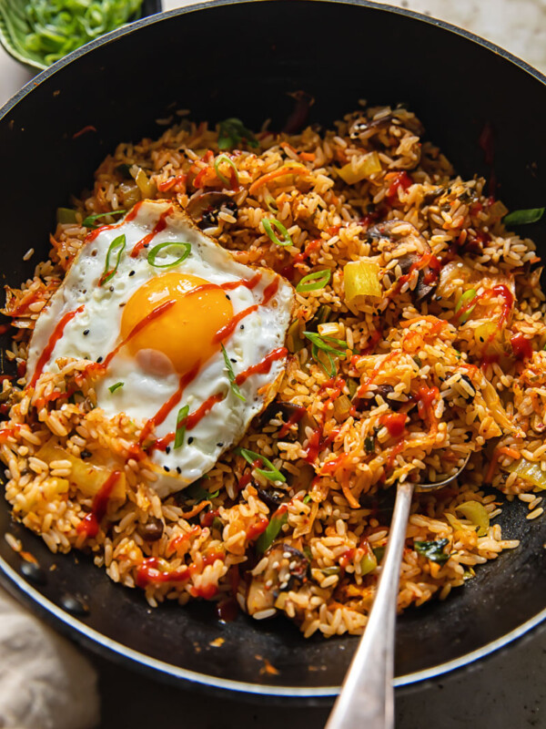 Wok with a spoon in fried rice with a fried egg on top