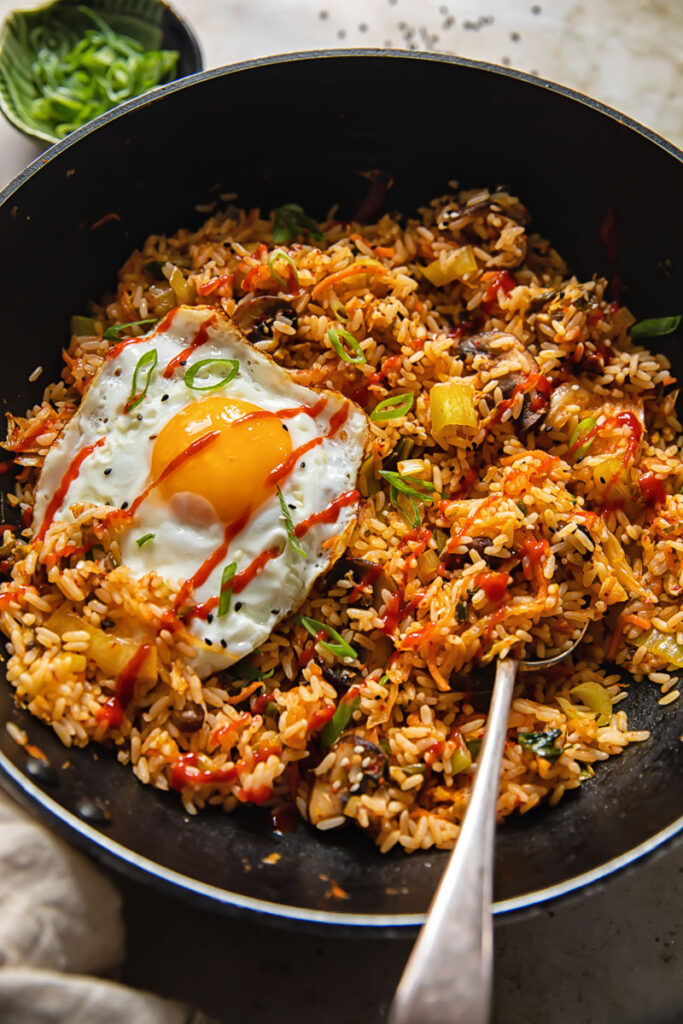 Wok with a spoon in fried rice with a fried egg on top