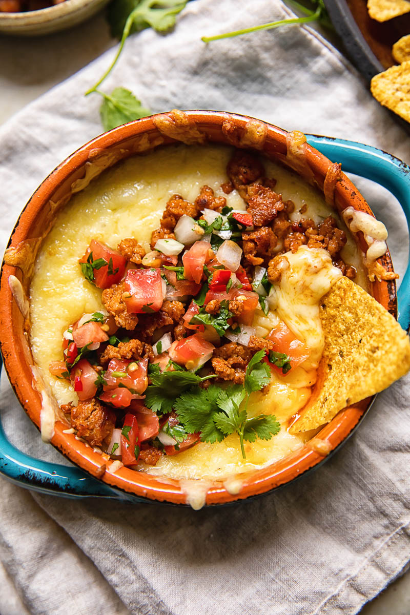 Dish of queso fundido with chorizo with a tortilla chip