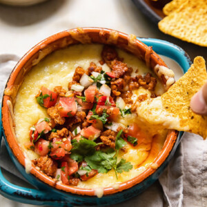 tortilla chip being dipped into dish of queso fundido with chorizo