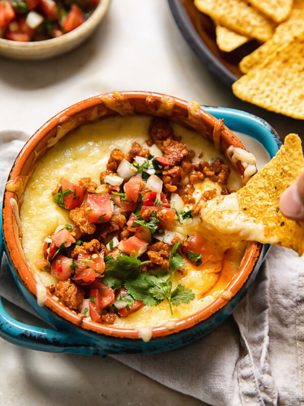tortilla chip being dipped into dish of queso fundido with chorizo