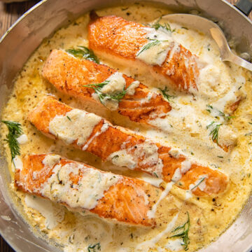 pieces of salmon in a creamy sauce with dill on top