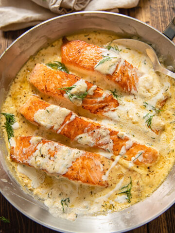 pieces of salmon in a creamy sauce with dill on top