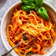 Top down of a bowl of pasta with basil and tomato and mascarpone basil sauce