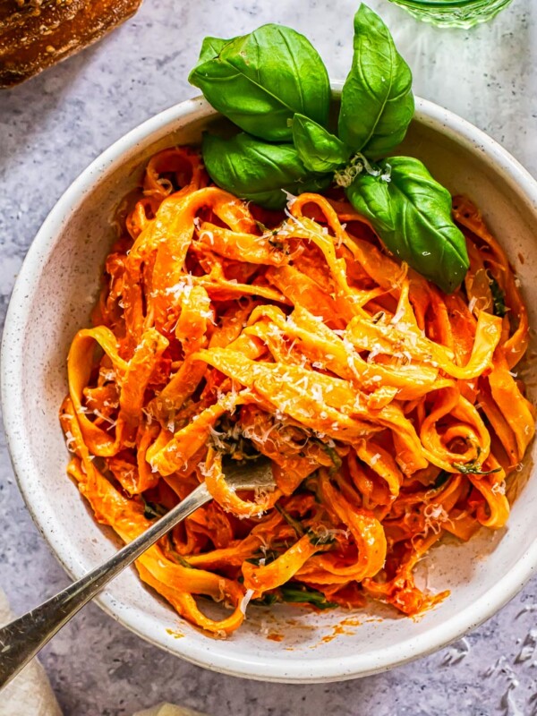 Top down of a bowl of pasta with basil and tomato and mascarpone basil sauce