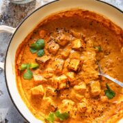 large pan of paneer tikka masala beside bowl of cilantro