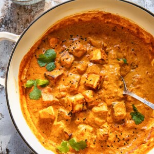 large pan of paneer tikka masala beside bowl of cilantro