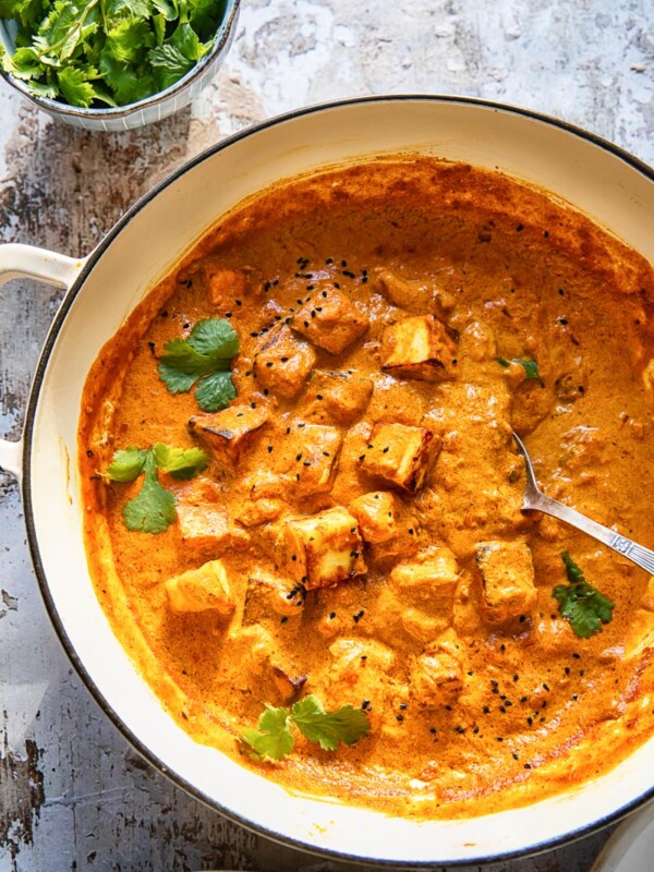large pan of paneer tikka masala beside bowl of cilantro
