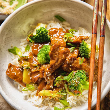 bowl of beef and broccoli stir fry with chop sticks