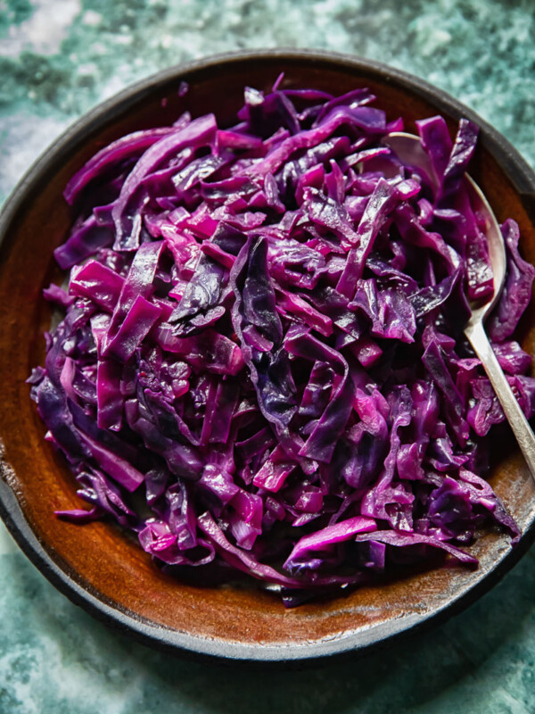 Top down view of braised red cabbage on a plate with bacon lardons and juniper berries
