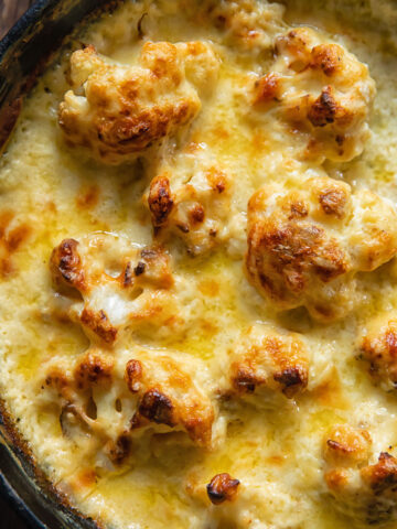 Top down view of cauli florets in a pan covered in cheesy Mornay sauce
