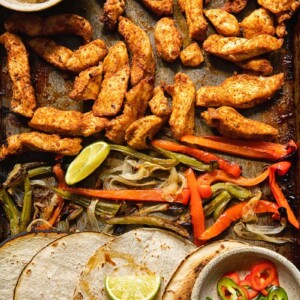 Top down view of tortillas and fajita toppings on a baking sheet