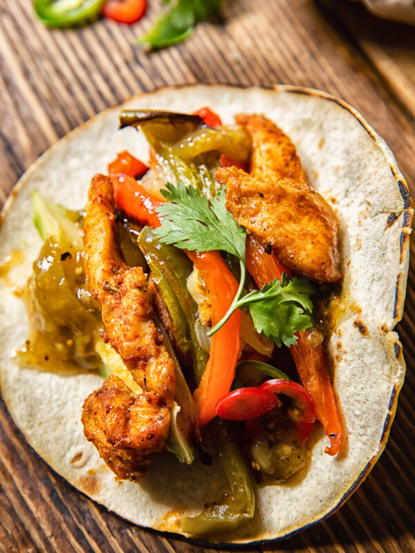Top down view of a chicken fajita with salsa and roasted peppers