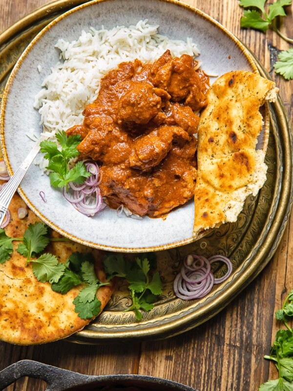 top down of a bowl of rogan josh on top of white rice with a piece of naan