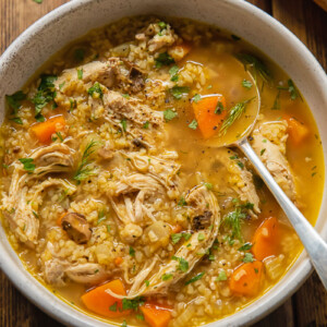 Top down view of chicken and mushroom soup in a bowl with bulgar and fresh dill