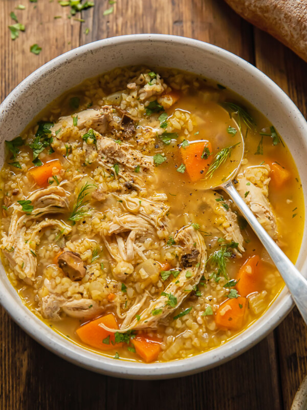 Top down view of chicken and mushroom soup in a bowl with bulgar and fresh dill