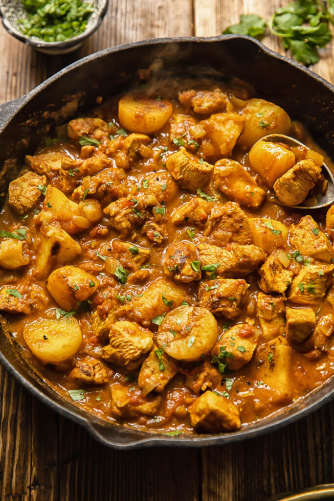 Top down view of chicken curry in a pan with potatoes