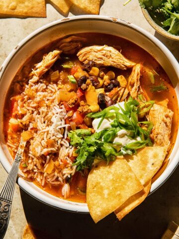 Top down view of chicken tortilla sop with rice, beans, corn and green onions in a bowl