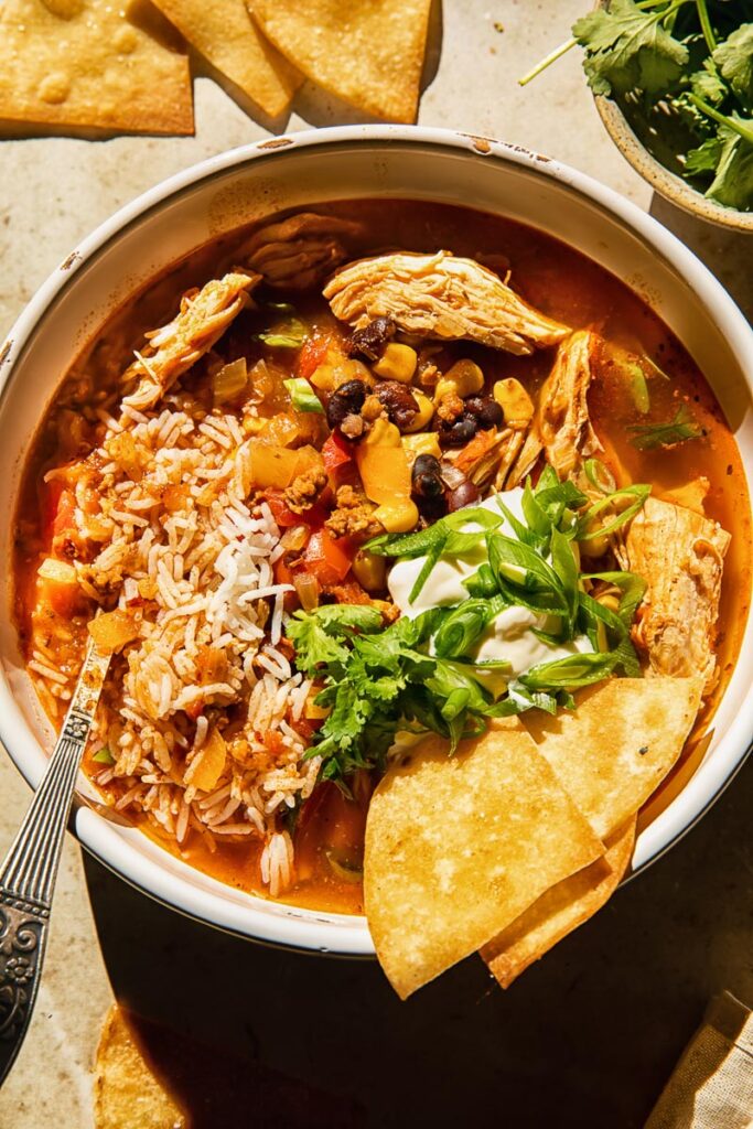 Top down view of chicken tortilla sop with rice, beans, corn and green onions in a bowl