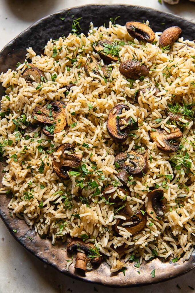 Close up of mushroom rice on a plate with parsley and dill