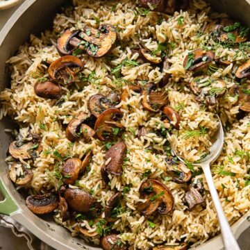 Top down view of mushroom rice in a pot topped with fresh parsley
