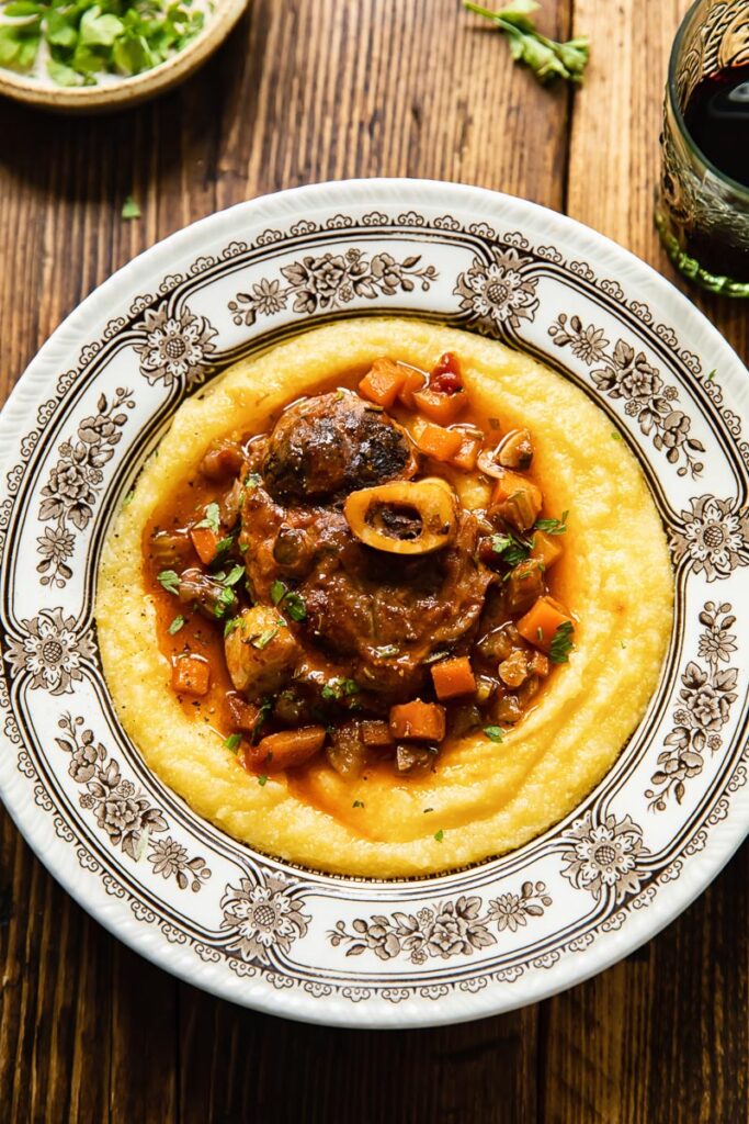 Top down view of pork osso buco served over creamy polenta in a bowl