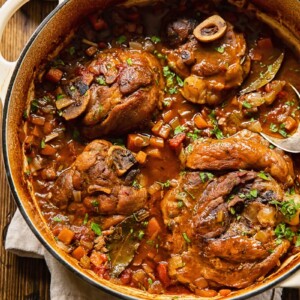 Pork osso buco in a pot with cut up carrots and celery