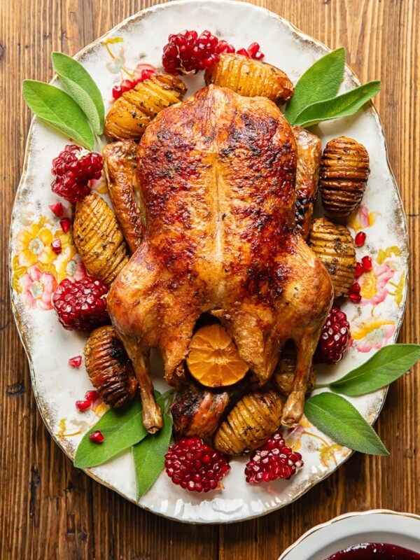 Top down view of roasted duck with potatoes and cranberries next to gravy