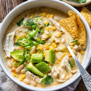 Top down view of white chicken chili with corn, chillies and avocado in a bowl