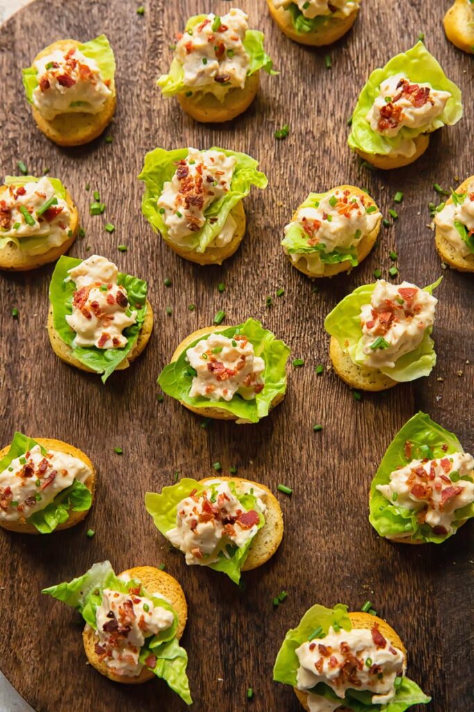 Top down view of multiple chicken Caesar crostinis next to each other with bacon bits