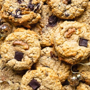 Top down shot of many cowboy cookies stacked on top of each other on a cutting board