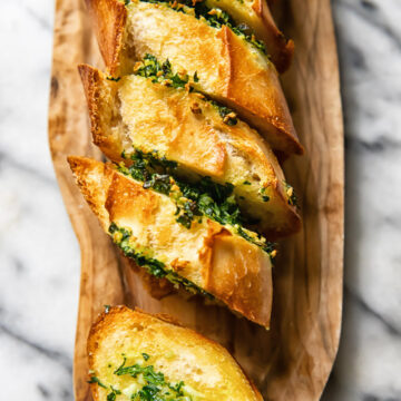 Top down shot of slices of garlic bread layered next to each other on a cutting board