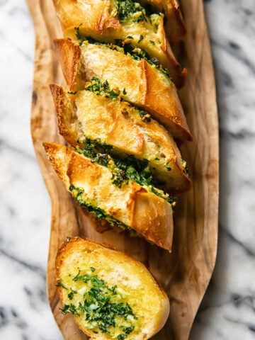 Top down shot of slices of garlic bread layered next to each other on a cutting board