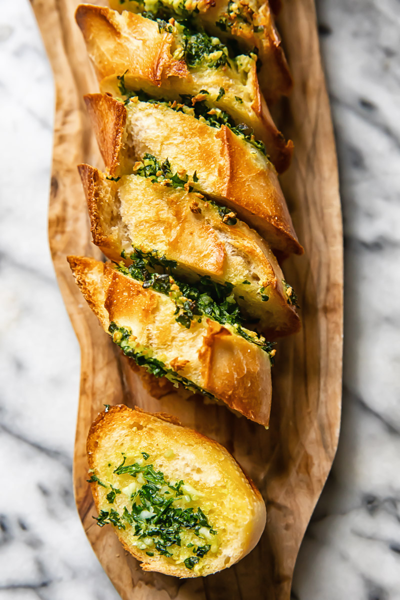 Top down shot of slices of garlic bread layered next to each other on a cutting board