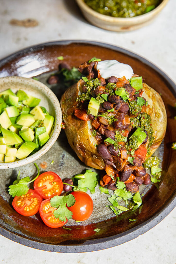 Plate with jacket potato with added toppings and avocado