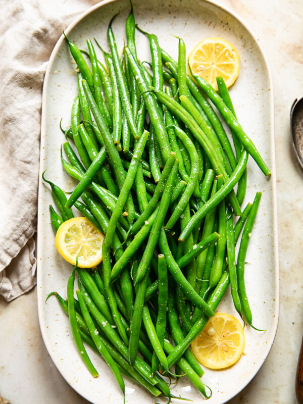 Platter of green beans with lemon butter, with visible lemon slices.