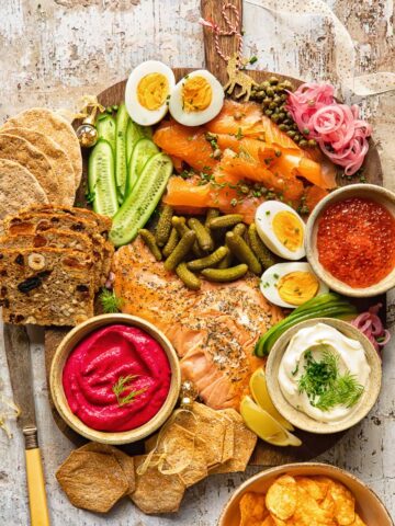 Top down view of grazing board made of smoked salmon, cucumbers, pickles and capers