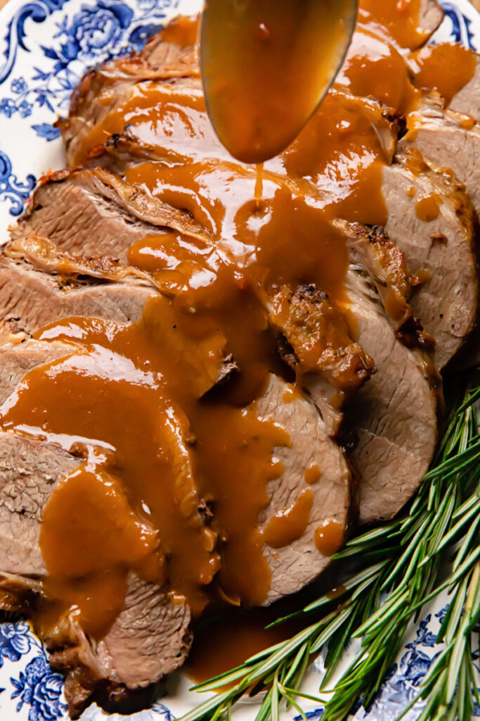 Close up shot of gravy being drizzled over roast beef