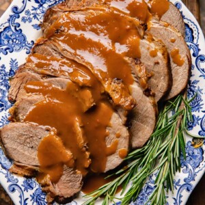 Top down shot of slow cooker roast beef on a plate with gravy and rosemary