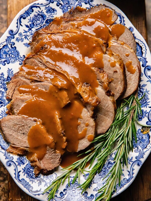 Top down shot of slow cooker roast beef on a plate with gravy and rosemary