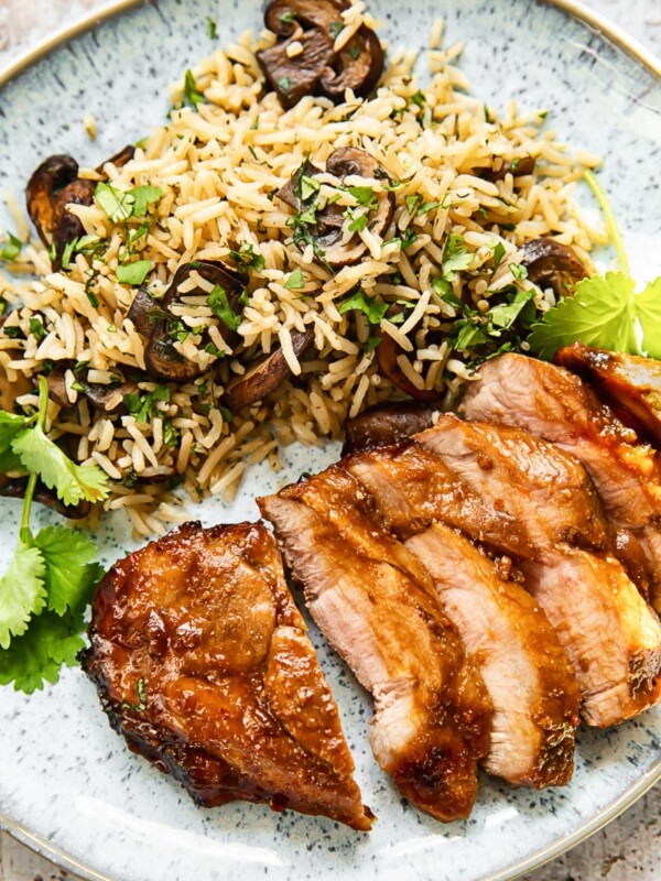 Top down view of boneless porck chop slices on a plate with herbed mushroom rice