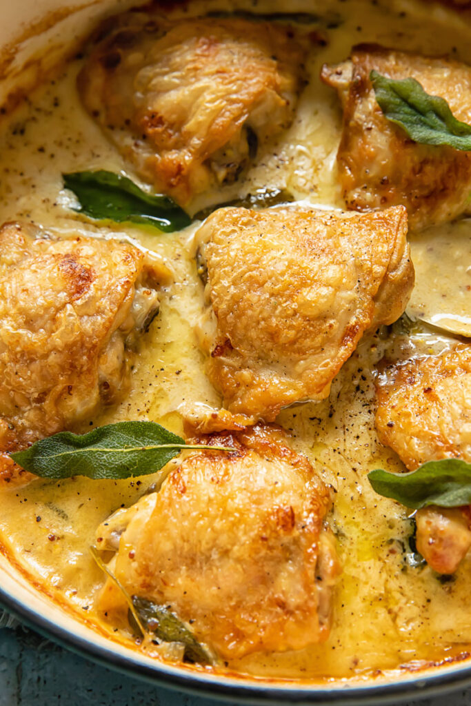 Close up shot of braised chicken with creamy sage sauce in a pot