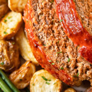 Close up shot of slices of classic meatloaf on a plate with potatoes and beans