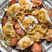 Bowl of pierogies and sliced kielbasa topped with crispy caramelised onions
