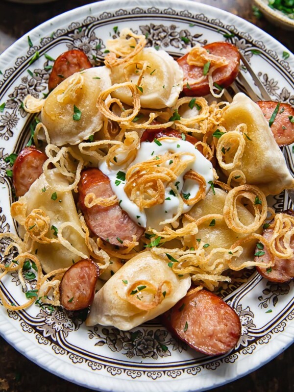 Bowl of pierogies and sliced kielbasa topped with crispy caramelised onions