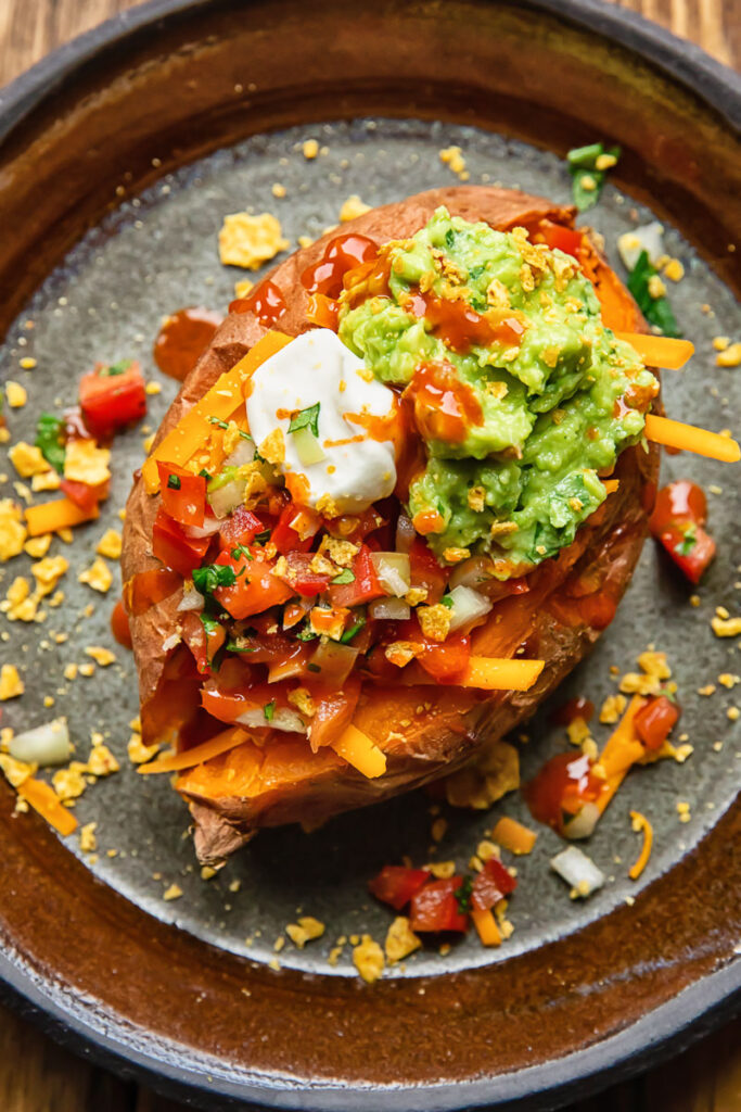 top down view of baked potato with sour cream, guacamole and salsa toppings